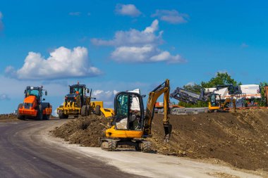 Yolda çalışan makinelerin panoraması. Yeni bir yol inşa ediyorum. Çalışan farklı yol ekipmanları.