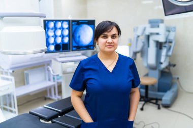 Modern cerrahi ekipmanlarının yanında poz veren kadın doktor ya da hemşire. Bulanık arkaplanda robotik ekipman.