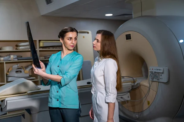 Healthcare, medical and radiology concept - two female doctors looking at x-ray.