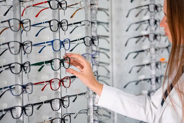 現代の眼科店で眼鏡をかけたショーケース 眼鏡をかけた女性の手 — ストック写真