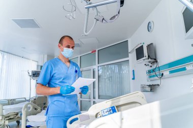 Maskeli doktor. Hastanedeki özel modern oda. Modern tıp yatağı ve modern koğuşta özel bir cihaz..