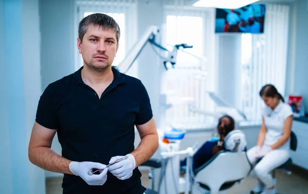身穿黑色衬衫的牙医对着相机摆姿势 医疗小组正在进行背景调查 现代口腔科 冰的牙齿学 — 图库照片