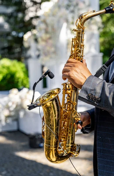 Hands of man playing saxophone. Close up view of the hands of a male saxophonist playing a tenor saxophone. Jazz, classical and blues music at wedding.