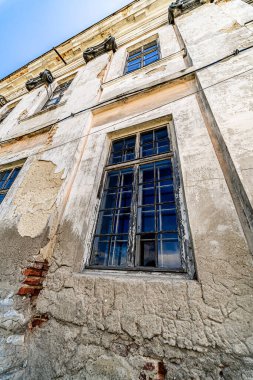 Boya soyan eski bir duvar. Çizik lekeli alçı ve kapalı pencereler. Aşağıdan görüntüle.
