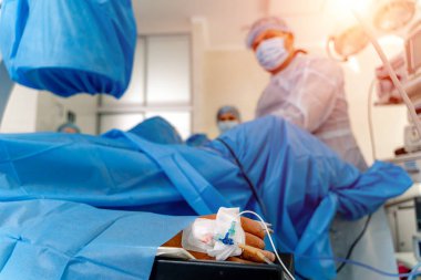 Ameliyat masasında yatan hastanın eli. Elinde anestezi olan bir şırıngayla sonda. Yakın çekim..