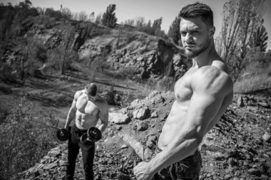 Kayalık arka planda tişörtsüz iki yakışıklı ve güçlü adamın portresi. Açık hava fotoğrafı. Erkek güzellik konsepti. Yakın çekim..