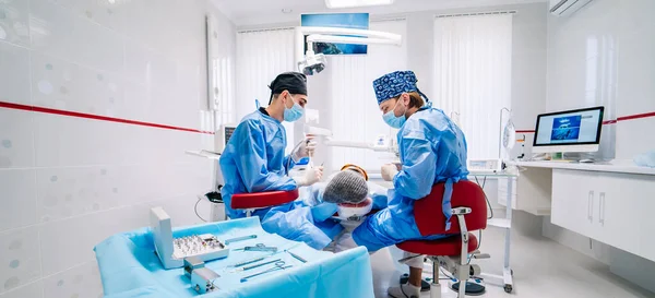 치과의 진료소에서 환자의 치아를 선택적 초점은 측면에서 수술복을 의사들 — 스톡 사진