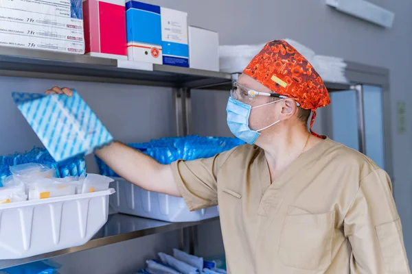 Stocked shelves of medical scrubs in storeroom. Assistant gets stuff. Scrubs, medical masks, antiseptic, health care and prevention methods. Sanitizer.