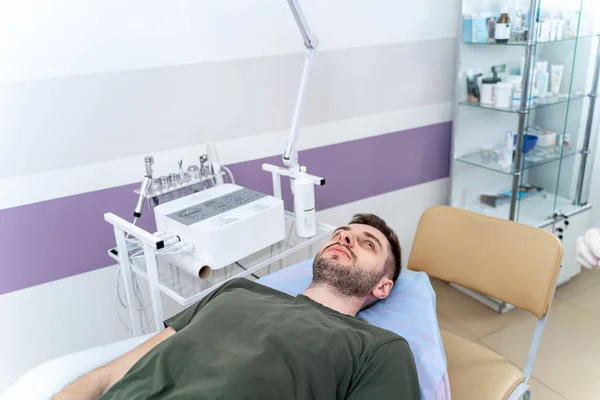 男人躺在美容外科诊所准备在温泉沙龙接受美容师的面容滋养面罩 — 图库照片