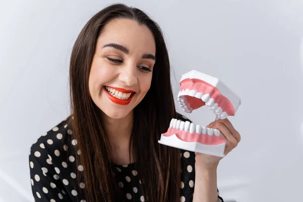 Girl looking to a dental educational jaw. Plastic jaw in girl`s hands. Funny emotions.
