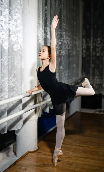 穿着黑色衣服的优雅的年轻芭蕾舞演员站在她的脚尖上 弯腰在工作室的背景下 这张照片很好地反映了古典芭蕾舞艺术无与伦比的美丽 — 图库照片
