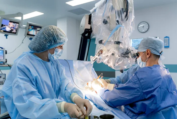 Surgical room in hospital with robotic technology equipment. Machine arm in neurosurgeon`s hands. Surgery operation room.