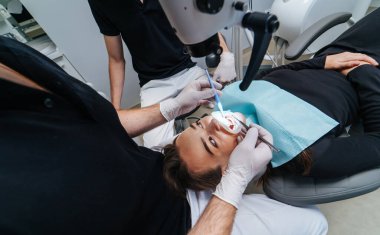 Diş hekimi hastanın dişlerini diş mikroskobuyla inceliyor. Modern tıbbi ekipmanlar. Oral tedavi konsepti. - Yakın çekim. Seçici odak.