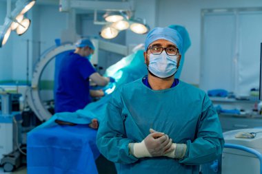 Mavi önlüklü doktor maske, gözlük ve lateks eldiven takıyor. Ameliyathane. Modern cerrahi ekipmanı.
