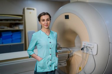 Radyoloji uzmanı tomografi ya da MR makinesinin yanında poz veriyor. Hastanede profesyonel ve modern teknisyen.