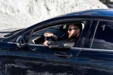 Çekici, zarif, ciddi adam iyi araba kullanıyor. Lüks arabalı maço adam. Seçici odak.