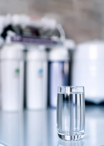 Ev filtreleme sistemi. Su arıtma kavramı. Evde su filtresi kullanılıyor. Bulanık arkaplanda bir bardak temiz su ve filtre..