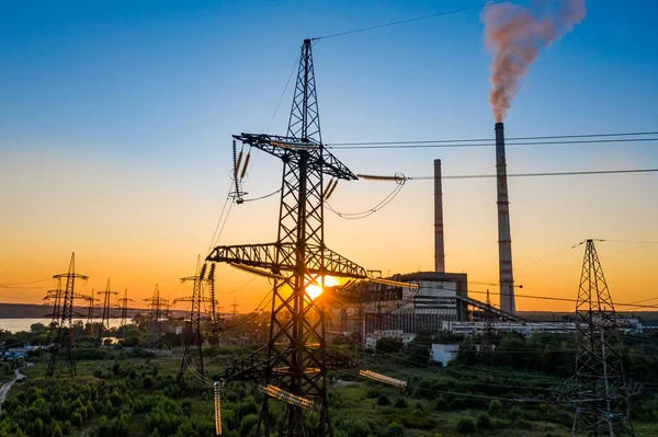 Energy distribution network. Electricity pylons against orange and yellow sunset. Selective focus.