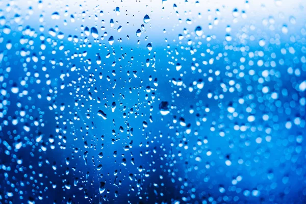 Druppels Water Een Verlichte Glazen Achtergrond Regenwaterdruppels Lopen Naar Beneden — Stockfoto