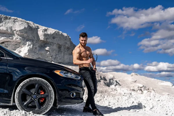近照一个赤身裸体的年轻人站在外面的汽车旁边 白色采石场背景 — 图库照片