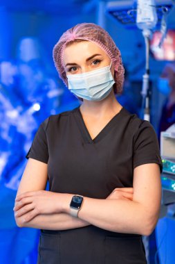 Cerrah operasyon için hazırlanıyor. Ameliyat maskesini takmış bir sağlık görevlisi ameliyata hazır bir ameliyathanede güvenle bekliyor..