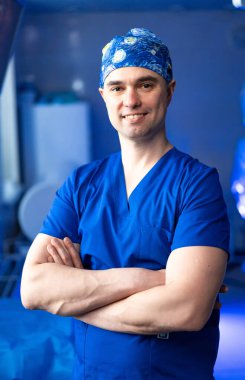 Önlüklü doktor ameliyata hazırlanıyor. Mavi önlüklü ve kepli bir sağlık görevlisi ameliyata hazır bir şekilde ameliyathanede duruyor..