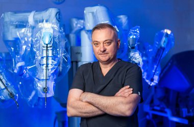 Robot destekli yetenekli cerrah. Kendine güvenen bir cerrah, yüksek teknoloji ürünü bir ameliyathanede kollarını kavuşturarak durur..