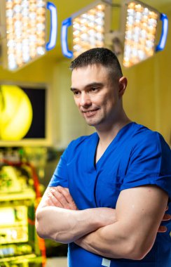 Modern ameliyathanede kendine güvenen bir cerrah. Çapraz kollu sakin bir cerrah, hazır ve nazır bir ameliyathanede duruyor..