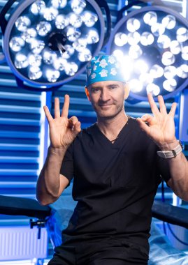 Cerrahi sağlık çalışanı. Kendine güveni tam bir sağlık çalışanı, modern cerrahi odasında parlak ışıklar altında olumlu bir hareket sergiliyor..