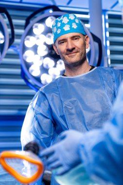 Cerrah modern odada hazır bekliyor. Önlüklü bir tıp uzmanı, parlak ışıkları olan yüksek teknolojili bir ameliyathanede ameliyata hazırlanıyor..