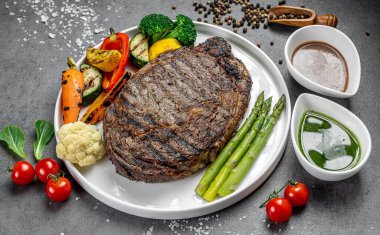 Sebzeli ve soslu ızgara biftek. Lezzetli ızgara biftek yanında çeşitli taze sebzeler ve beyaz tabakta zengin soslar..