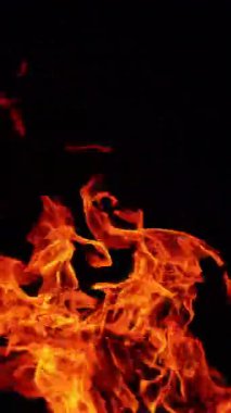 Alevler ve kıvılcımlarla yanan güzel bir ateş. Karanlıkta parla. Dikey video