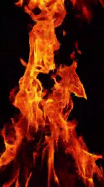 Kamp ateşi karanlığa yükseliyor. İzole edilmiş şenlik ateşi yerde yanıyor. Dikey video