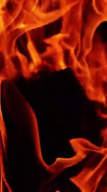 Şenlik ateşinde alevler içinde siyah odun parçaları. Siyah arka plandaki kamp ateşinin yakın görüntüsü. Dikey video