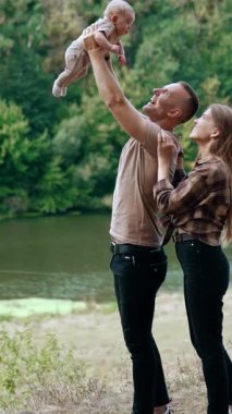 Açık havada harika bir aile hayatı. Yeni doğmuş bebeği olan mutlu, komik bir aile. Dikey video