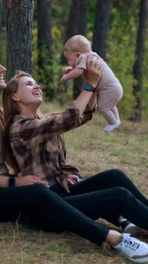 Yeni doğmuş bebeği olan mutlu, komik bir aile. Açık havada harika bir aile hayatı. Dikey video