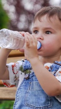 Çocuk parkında şirin bir çocuk. Öğrenmek ve küçük bebeği oynamak. Dikey video