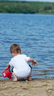River Beach 'li küçük çocuk eğleniyor. Suyun üstünde oynayan tatlı bir erkek bebek. Dikey video