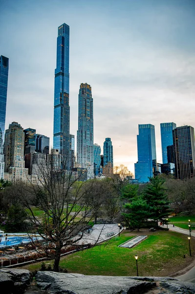 Park 'ın üzerindeki New York gökdelenleri kulesi. Gün batımında sakin bir atmosfer oluşturan uzun binalar Central Park 'taki sakin bir manzaranın etrafını sarıyor..