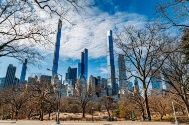 Central Park üzerinde kış gökdelenleri. Central Park 'taki çıplak ağaçlar gökdelenleri masmavi gökyüzüne karşı çerçeveletiyor, New York' ta kışın güzelliğini vurguluyorlar..