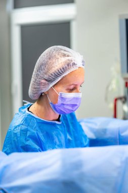 Tıbbi profesyonel ameliyat. Cerrahi giysiler içinde kendini adamış bir tıp uzmanı steril bir ortamda ameliyat sırasında bir hastaya odaklanır..