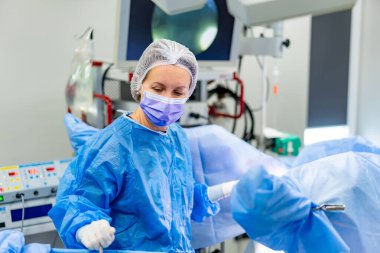 Hastanede cerrah ameliyatı. Yetenekli bir cerrah, elimizdeki prosedüre odaklanmış, parlak, yüksek teknolojili bir cerrahi odasında çalışır..