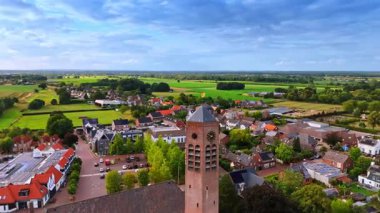 Hollanda kırsalının havadan görünüşü. Gökyüzünün altında yeşil tarlaları ve saat kulesi olan bir Hollanda köyünün cazibesini gösteren pitoresk bir hava manzarası..