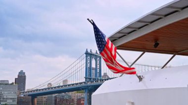 Şehir köprüsü yakınındaki Amerikan bayrağının görüntüsü. Bir Amerikan bayrağı gün boyunca gökyüzünü ve köprüyü gösteren bir tekneden dalgalanır..