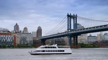 Manhattan Köprüsü 'nün altından feribot geçiyor. Manhattan Köprüsü 'nün altından bir feribot geçiyor. Arkaplanda binalar var..