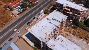 Yeni inşaat alanı gelişimi. İşçiler, açık gökyüzünün altında işlek bir yol boyunca devam eden inşaatla meşgul..