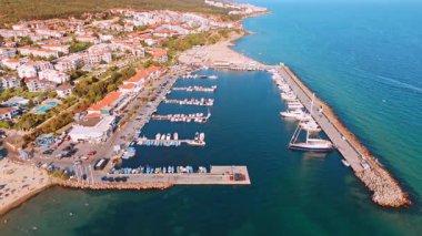Açık denizde tekneleri olan sahil marinası. Parlak bir gökyüzünün altında, bir yaz günü manzaralı bir plaja bitişik, canlı bir marina manzarası..