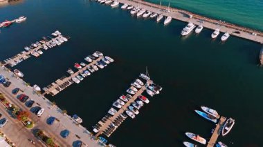 Tekneli gün batımı marinası. Gün batımında bir marinaya çok sayıda tekne yanaşır, sakin sular canlı gökyüzü renklerini yansıtır..