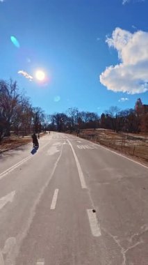 Central Park 'ta kış yürüyüşü. İnsanlar Central Park 'ta güneşli bir kış gününün keyfini çıkarırlar, açık mavi gökyüzünün altında geniş yollar boyunca yürürler..