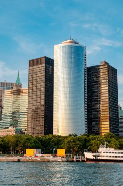 Modern gökdelenler Manhattan 'daki güneş ışığını yansıtır. Manhattan 'da, parlak gökdelenler gün ışığında parlıyor, rıhtımdan yansıyor ve çarpıcı bir manzara yaratıyor..